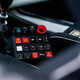 close-up interior photo of a racing-style control panel in the center console of a subaru 2.5rs built for rally racing. buttons for ignition, engine start, turn signals, headlights, wipers and defroster can be seen